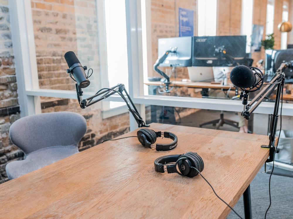 Photo by Austin Distel two black headphones on brown wooden table
