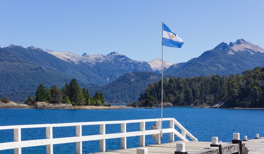 Photo by Fernando Távora white and blue flag on wooden dock near body of water during daytime