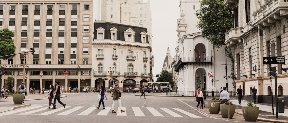 woman crossing pedestrian lane between tall buildings