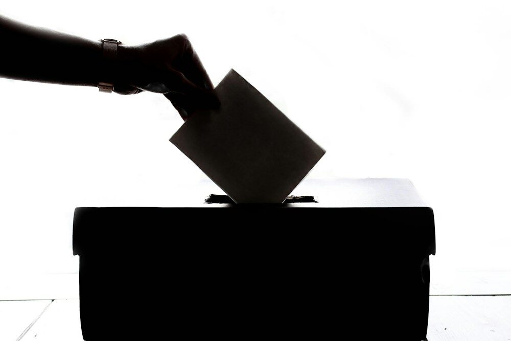 Photo by Element5 Digital a person is casting a vote into a box